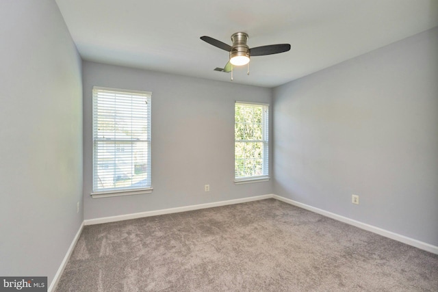 carpeted spare room featuring baseboards and ceiling fan