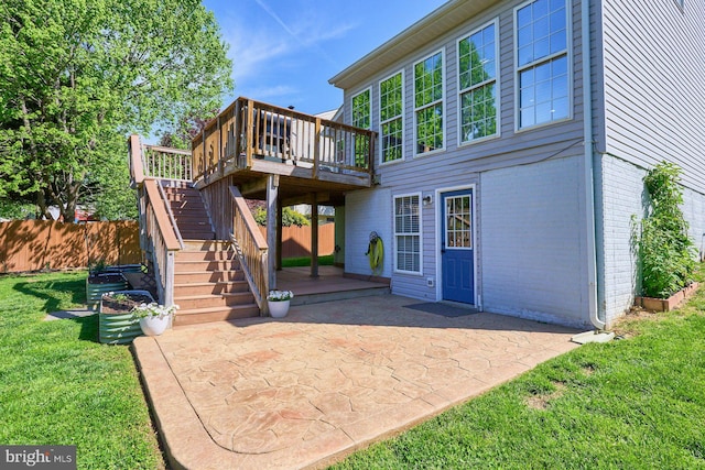 rear view of house featuring a wooden deck, stairs, brick siding, a patio area, and a lawn