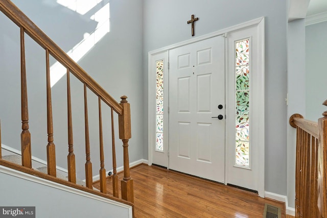foyer with stairs, baseboards, visible vents, and wood finished floors