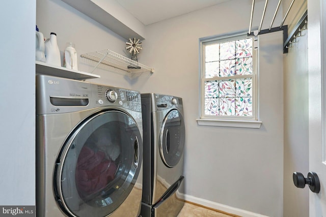 laundry area with washing machine and clothes dryer, laundry area, baseboards, and tile patterned flooring