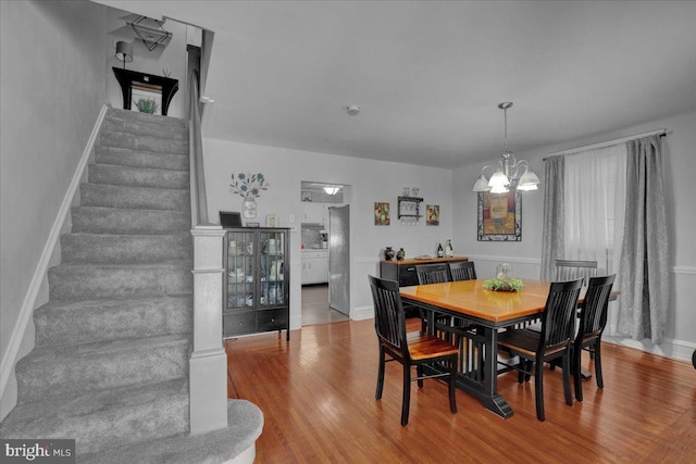 dining area featuring stairs, baseboards, a notable chandelier, and wood finished floors