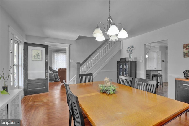 dining space featuring a notable chandelier, wood finished floors, and stairway