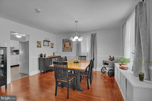 dining space with baseboards, wood finished floors, and a notable chandelier