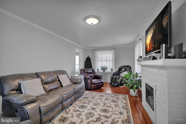 living area with ornamental molding, a brick fireplace, and wood finished floors