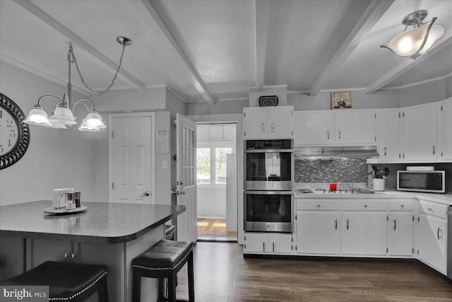 kitchen with beam ceiling, stainless steel appliances, white cabinetry, backsplash, and under cabinet range hood