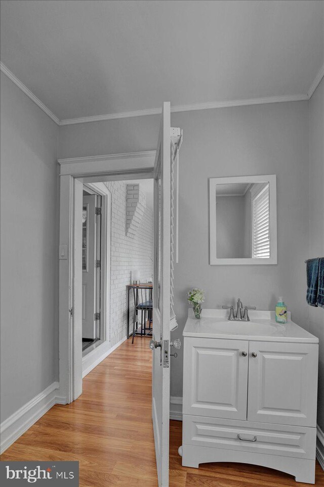 bathroom with crown molding, baseboards, wood finished floors, and vanity