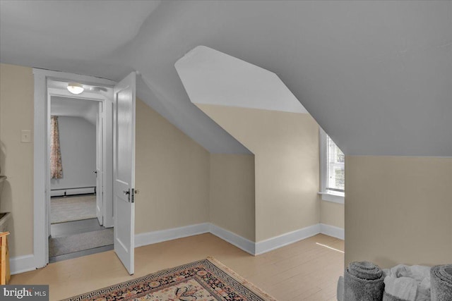 additional living space with baseboards, light wood finished floors, lofted ceiling, and baseboard heating