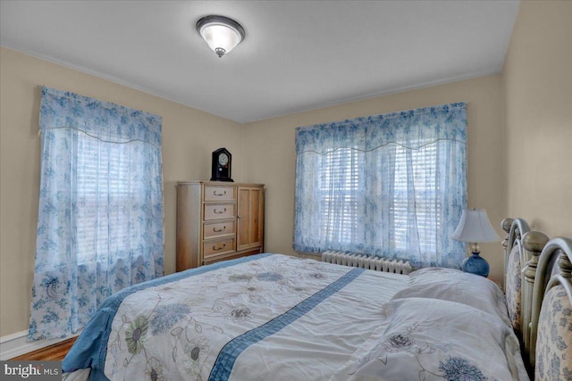 bedroom with radiator heating unit, baseboards, and wood finished floors