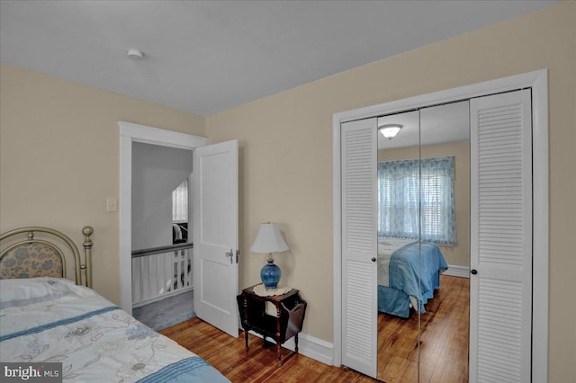 bedroom with baseboards, wood finished floors, and a closet
