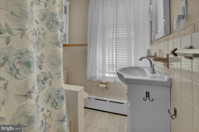 full bathroom featuring vanity, tile walls, and a baseboard heating unit
