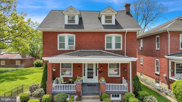 traditional style home with fence, a front lawn, brick siding, a chimney, and covered porch