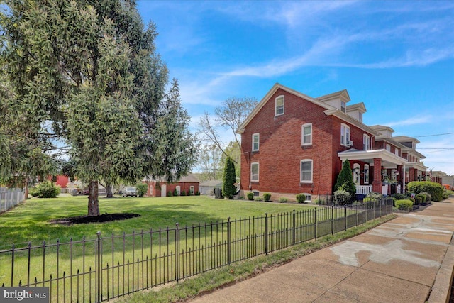 view of side of home with a yard, brick siding, fence private yard, and a porch