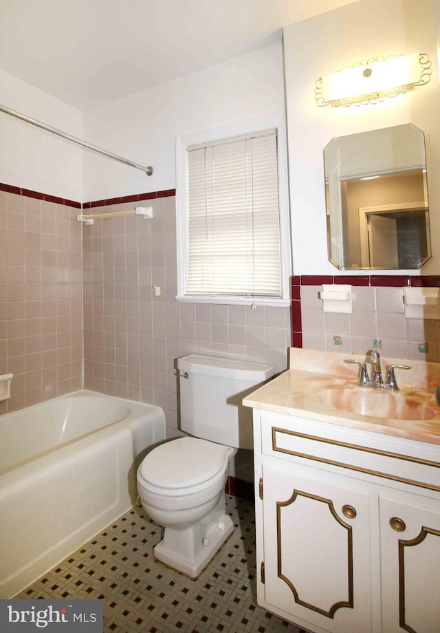 full bath with tile walls, toilet, vanity, tub / shower combination, and tile patterned floors