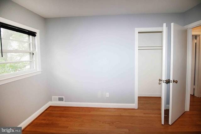 unfurnished bedroom with wood finished floors, a closet, and baseboards