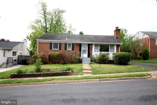 ranch-style home featuring brick siding, a chimney, and a front yard