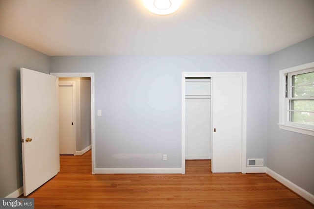 unfurnished bedroom featuring light wood finished floors, baseboards, and a closet