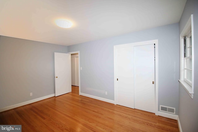 unfurnished bedroom featuring light wood-style flooring, baseboards, and a closet