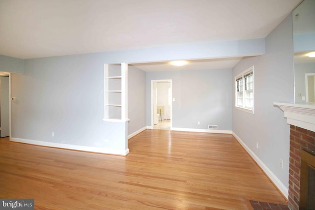 unfurnished living room featuring a fireplace, light wood-style floors, and baseboards