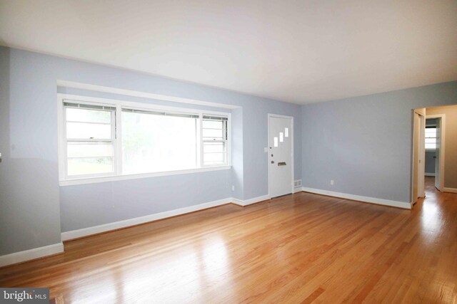 unfurnished living room featuring baseboards and light wood finished floors
