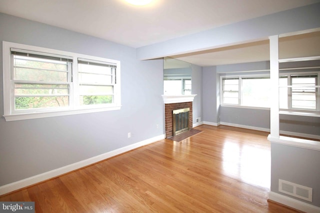 unfurnished living room featuring baseboards, light wood-type flooring, and a fireplace