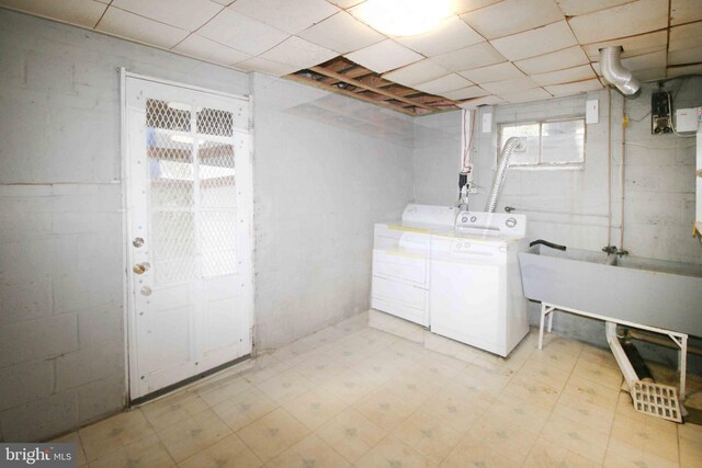 clothes washing area featuring washer and clothes dryer, light floors, healthy amount of natural light, and concrete block wall