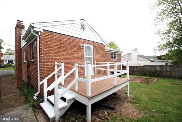 rear view of property featuring a wooden deck, brick siding, and a chimney