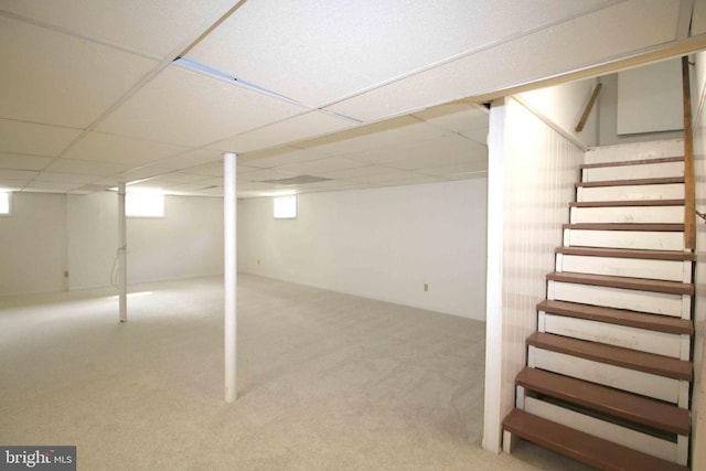 below grade area featuring a drop ceiling, stairs, and carpet flooring