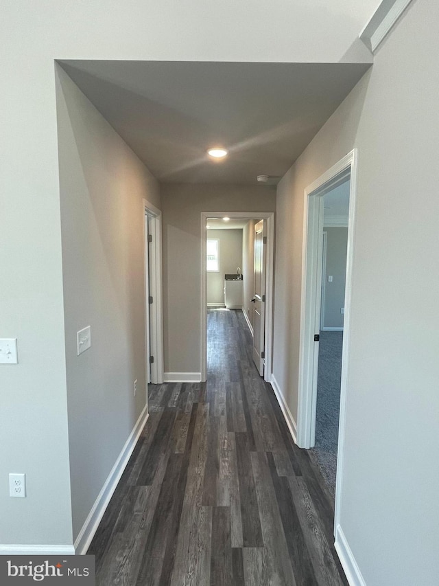 corridor with baseboards and dark wood-type flooring