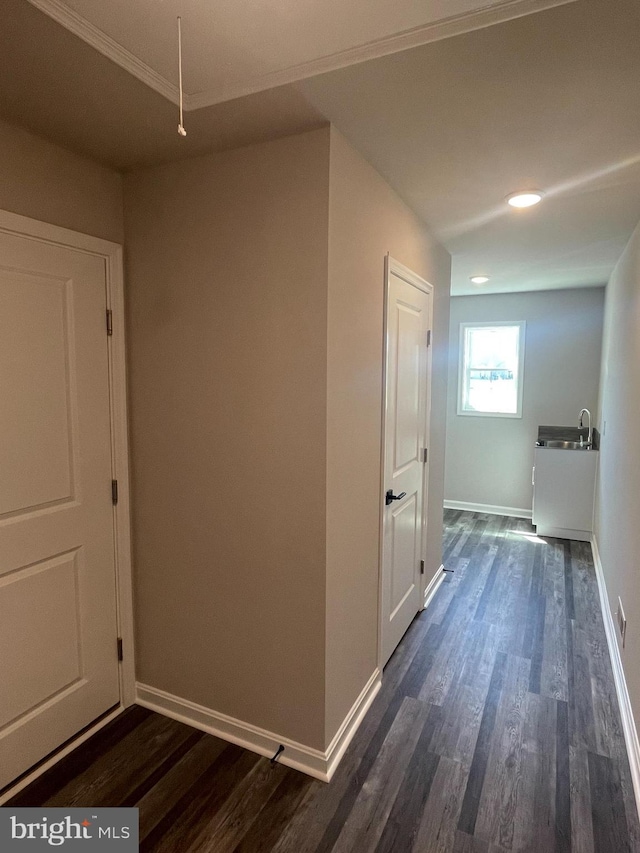 hall featuring attic access, dark wood finished floors, baseboards, and ornamental molding