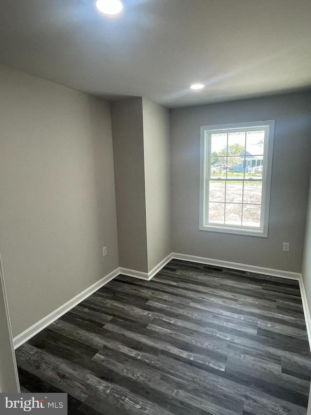 spare room with recessed lighting, baseboards, and dark wood-style flooring