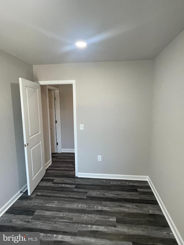 spare room featuring baseboards, dark wood-style flooring, and recessed lighting