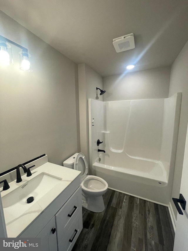 bathroom with toilet, washtub / shower combination, vanity, and wood finished floors
