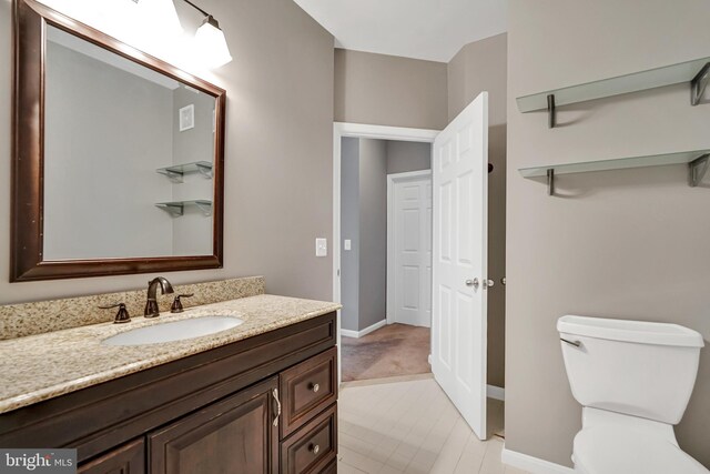 bathroom featuring vanity, toilet, and baseboards