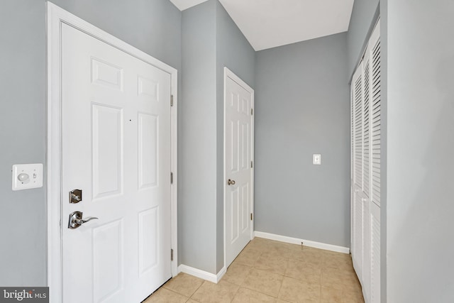 hall with baseboards and light tile patterned flooring