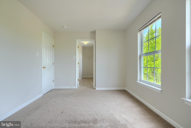 724 Tinker Rd, Middle River, MD 21220 - unfurnished bedroom with multiple windows, baseboards, a spacious closet, and carpet flooring