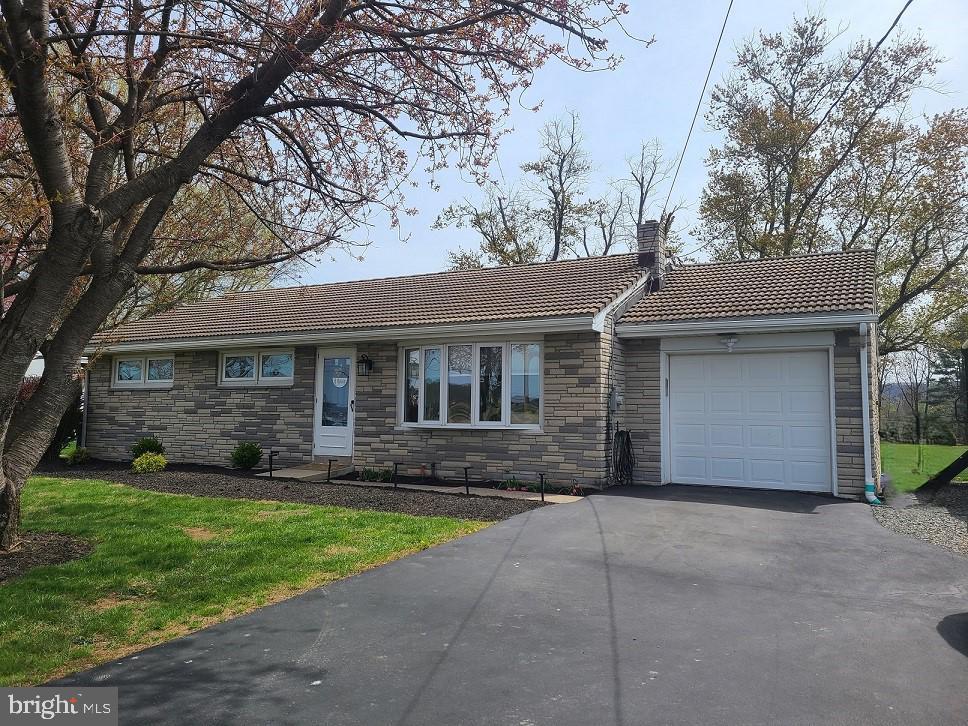322 Bertolet Mill Rd, Oley, PA 19547 - single story home featuring a tiled roof, stone siding, a chimney, an attached garage, and aphalt driveway