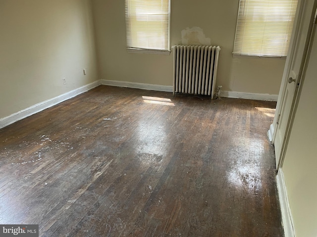 unfurnished room featuring radiator heating unit, baseboards, and hardwood / wood-style floors