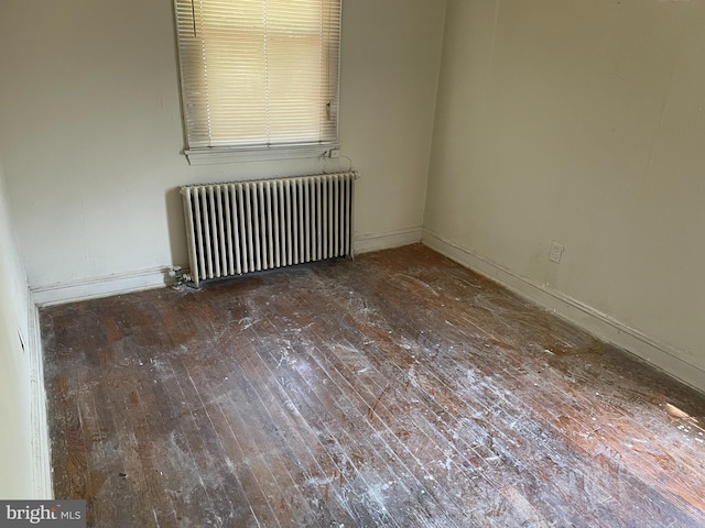 unfurnished room with radiator, hardwood / wood-style floors, and baseboards