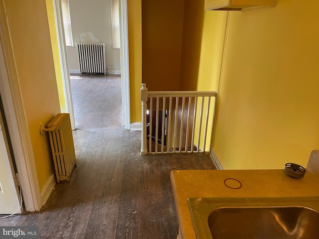hall with radiator heating unit, baseboards, and wood finished floors