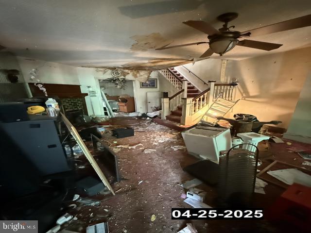 misc room featuring ceiling fan and stairs