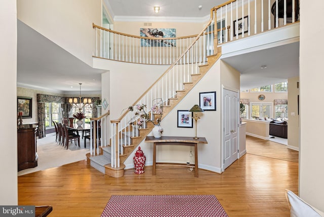 stairs featuring crown molding, a high ceiling, a wealth of natural light, and wood finished floors