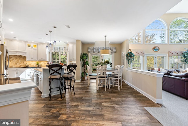 dining room featuring a healthy amount of sunlight, recessed lighting, dark wood-style floors, and baseboards
