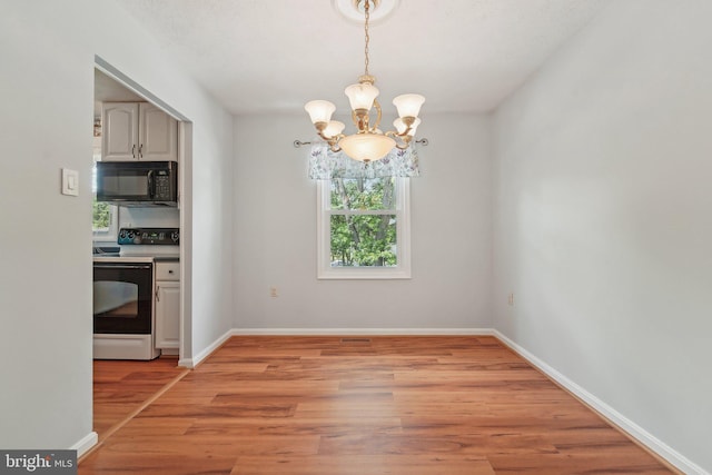 unfurnished dining area with a chandelier, healthy amount of natural light, light wood-style flooring, and baseboards