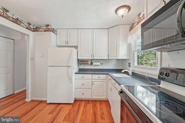 kitchen featuring electric range, freestanding refrigerator, black microwave, a sink, and light wood-type flooring