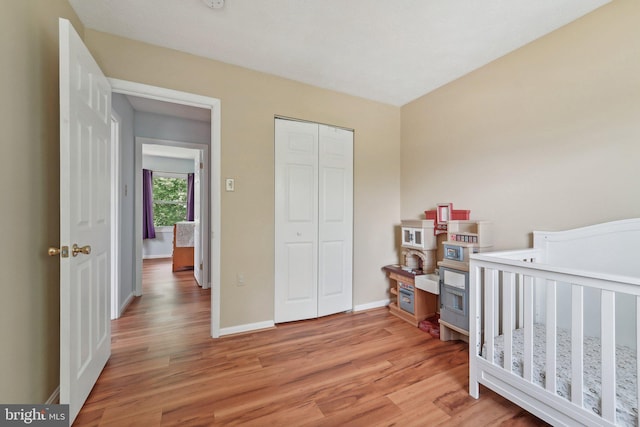 bedroom featuring light wood-style floors, baseboards, and a closet