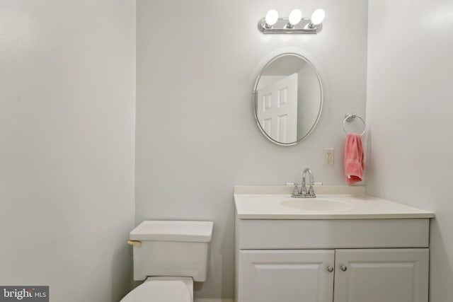 half bathroom featuring vanity and toilet