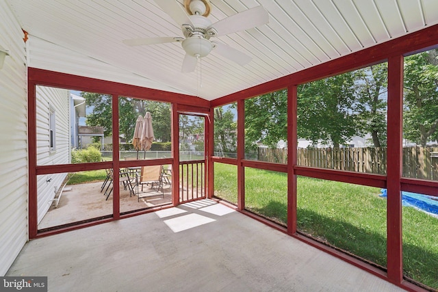 unfurnished sunroom with lofted ceiling, ceiling fan, and outdoor dining space