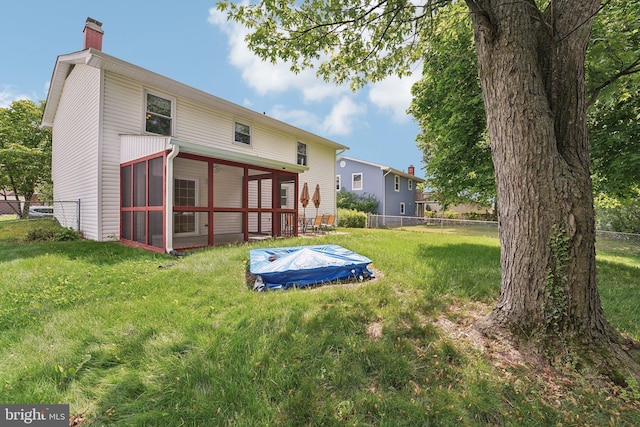 back of house featuring a chimney and a sunroom