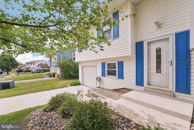 property entrance featuring a garage, driveway, and a lawn