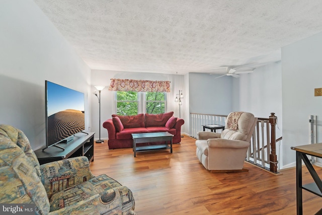 living area with a textured ceiling, wood finished floors, and baseboards